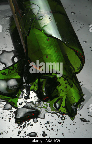 Broken wine bottle on reflective surface with spilled wine and liquid drops Stock Photo