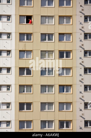 Man sitting in open window of tall block of flats Cardiff Wales UK Stock Photo