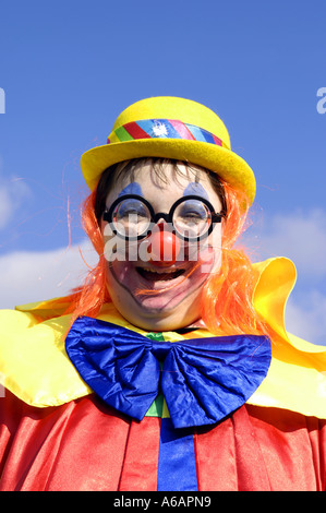 girl in clown outfit fancy dress carnival male blue sky day daylight colour color caucasian red nose colourful multicoloured smi Stock Photo