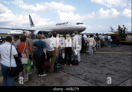 Plane passengers & hand luggage queuing to board Britannia airline jjet airliner flight to UK from Santo Domingo Airport Dominican Republic Caribbean Stock Photo