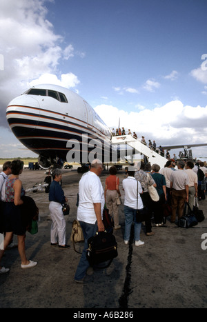 Plane passengers with hand luggage queuing to board Britannia jet airliner flight to UK 1980s view Santo Domingo Airport Dominican Republic Caribbean Stock Photo