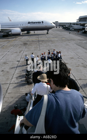 Plane passengers back view walk down air stairs leaving Britannia Airways Boeing holiday jet at Santo Domingo Airport to connect with Caribbean cruise Stock Photo