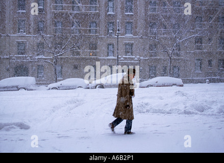Winter weather, a snowstorm in New York City. Parked cars buried in snow drifts, no traffic. A man walking alone on the street in upper manhattan. USA Stock Photo