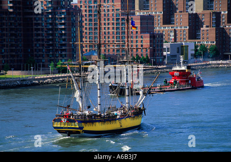Oil tanker or fuel tanker guided by tugboat. Vintage schooner with sails down on the the East River in Manhattan, New York City, USA. Stock Photo
