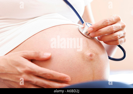 Pregnant woman holding stethoscope on belly, close up Stock Photo