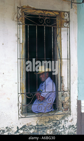Man sitting on a window ledge in Trinidad Cuba Stock Photo