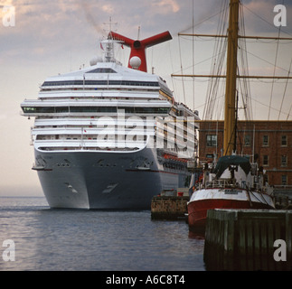 The cruise liner Carnival Victory departing Halifax Harbour, dwarfing a sailing boat. Stock Photo