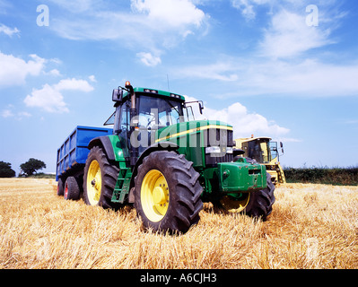 John Deere green tractor and new holland combine  harvester in cheshire field of cut crop Stock Photo