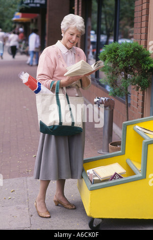 Mature woman shopping at an outdoors book stall Stock Photo