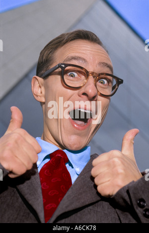 Businessman wearing glasses and giving thumbs up sign in front of office building Stock Photo