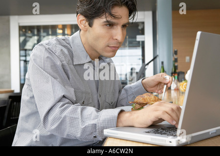 Man Using Laptop and Eating Stock Photo