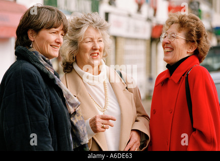 THREE MIDDLE AGED WOMEN CHATTING IN STREET Stock Photo
