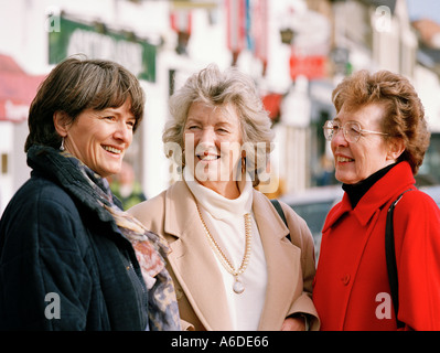 THREE MIDDLE AGED WOMEN CHATTING IN STREET Stock Photo