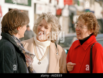 THREE MIDDLE AGED WOMEN CHATTING IN STREET UK Stock Photo