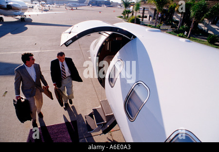 Two male executives with briefcases walk towards private jet Stock Photo