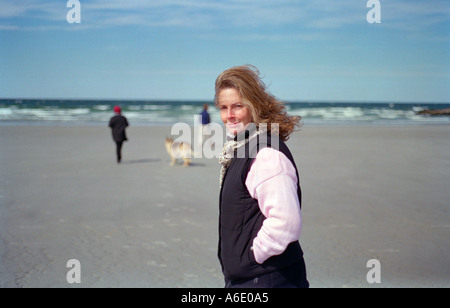 Woman dressed in warm clothes for off season excursion at the beach Stock Photo