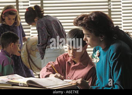 Latino female teacher helping caucasian and asian american students Stock Photo