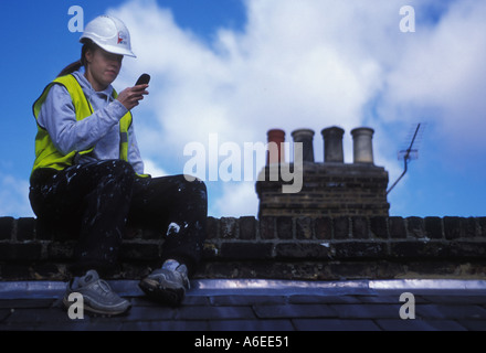 Female construction worker using mobile phone on rooftop Stock Photo