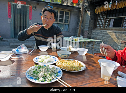 CHINA Chuandixia Chinese man eating family style lunch of many dishes Stock Photo