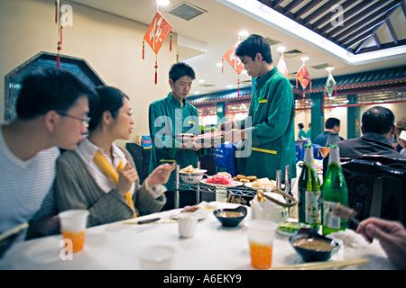 CHINA BEIJING Attentive waitstaff prepares Mongolian hotpot meal with a variety of food and condiments at popular restaurant Stock Photo