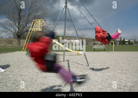 Young girl playing on swings at the playground Stock Photo