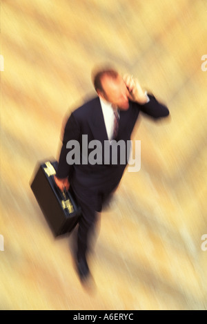 Businessman holding a briefcase and talking on a cellphone in a hurry Stock Photo