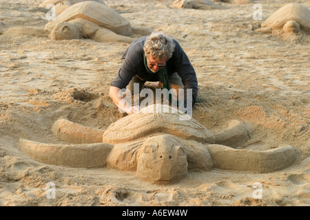 Sand artist making sculptures on the beach at Puri on Orissa's seashore in an appeal for 'Save the Turtles'. Stock Photo
