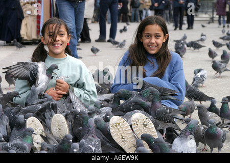 Two young girls enjoying feeding the pigeons, St Marks Square, Venice Stock Photo