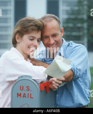 married couple reading greeting card at mailbox Stock Photo