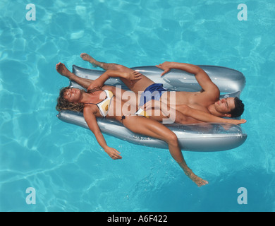 couple relaxing on raft in swimming pool Stock Photo