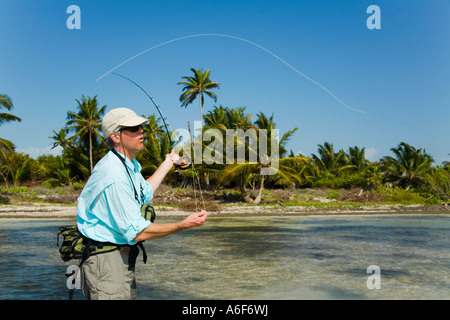 BELIZE Ambergris Caye Adult male fly fishing in flats along shoreline for bonefish wading in shallow water cast lefthanded Stock Photo