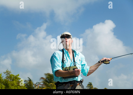 BELIZE Ambergris Caye Adult male fly fishing in flats along shoreline for bonefish casting with left hand rod and reel Stock Photo