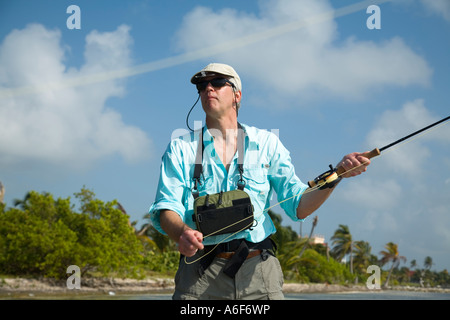 BELIZE Ambergris Caye Adult male fly fishing in flats along shoreline for bonefish cast with left hand rod and reel Stock Photo