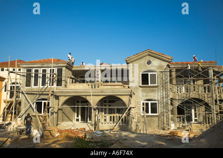 BELIZE Ambergris Caye Workmen on red tile roof and scaffolding construction of luxury accommodations Stock Photo