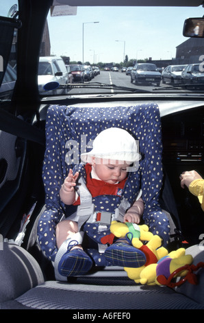 Child car safety seat rear facing as fitted in 1996 historical archive view of newborn baby boy travelling in mothers car along busy road England UK Stock Photo