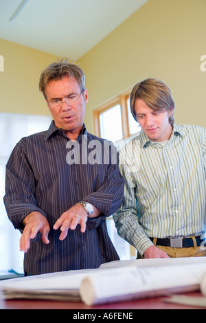 two architects in casual office with plans on table Stock Photo