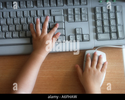 Child hands on a computer keyboard and mouse Stock Photo