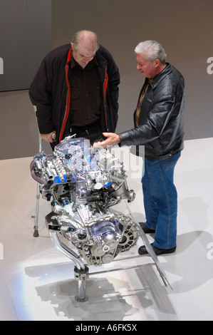Two men examining an engine at the Geneva Motor Show. Motion blur on one man's hand Stock Photo