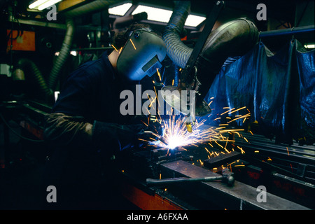 A welder at work in a factory manufacturing heavy duty shelving for warehouses. Stock Photo