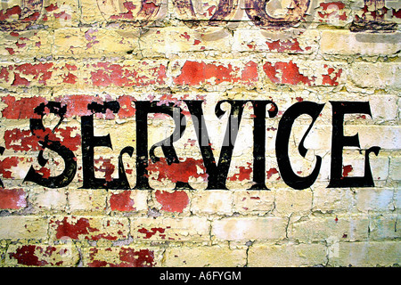 Peeling painted sign on old red brick wall reading service Stock Photo