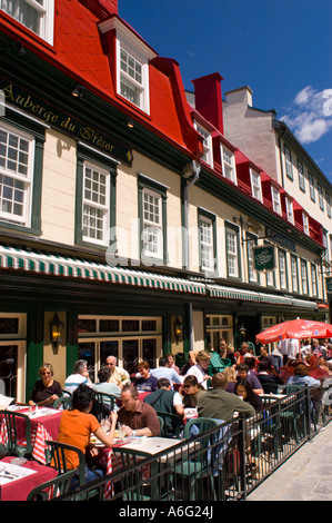 People eat and drink at outdoor tables in front of the Auberge du Tresor hotel and restaurant in Old Quebec Stock Photo
