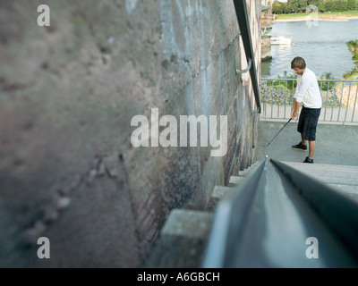 Man preparing to hit golf ball up steps Stock Photo