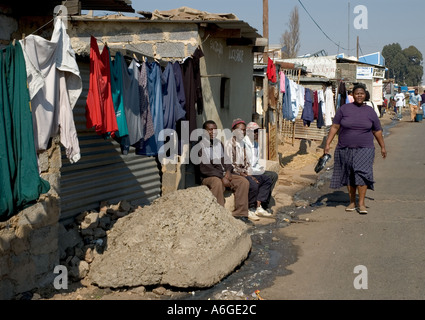 South Africa Johanesburg Alexandra Township people sitting in the street outside a shack with drying laundry Stock Photo