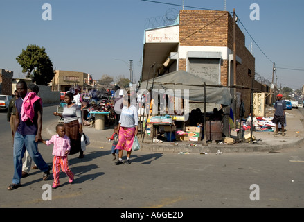 South Africa Johanesburg Alexandra Township people crossing the street at streets junction with corner building in bkgd Stock Photo