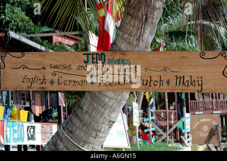 Wooden dive centre sign advertising multilingual instruction Coral Bay Perhentian Kecil Malaysia Stock Photo