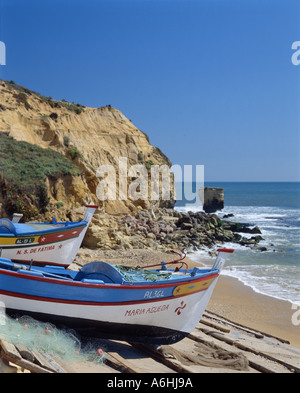 Portugal the Algarve, Olhos de Agua, fishing boats drawn up on beach, cliff in background Stock Photo