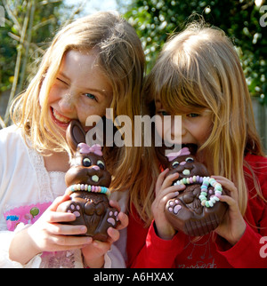 Girls holding chocolate bunny rabbits which have necklaces of sweets Easter gift Eating chocolate Stock Photo