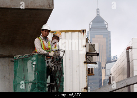 Hong Kong SAR, China, construction workers building the new ferry terminal, Central Plaza behind Stock Photo