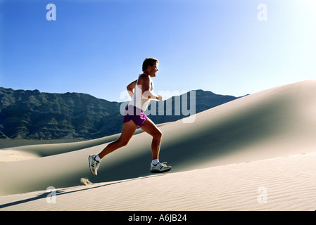 Model Released man running up sand dune in Death Valley National Park Stock Photo