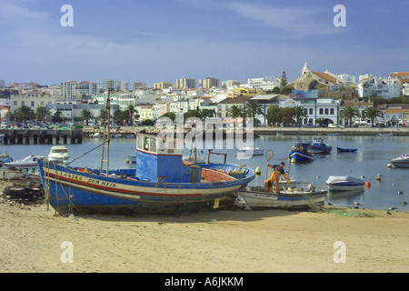 Portugal the Algarve; Lagos town seen over  fishing boats on shore Stock Photo